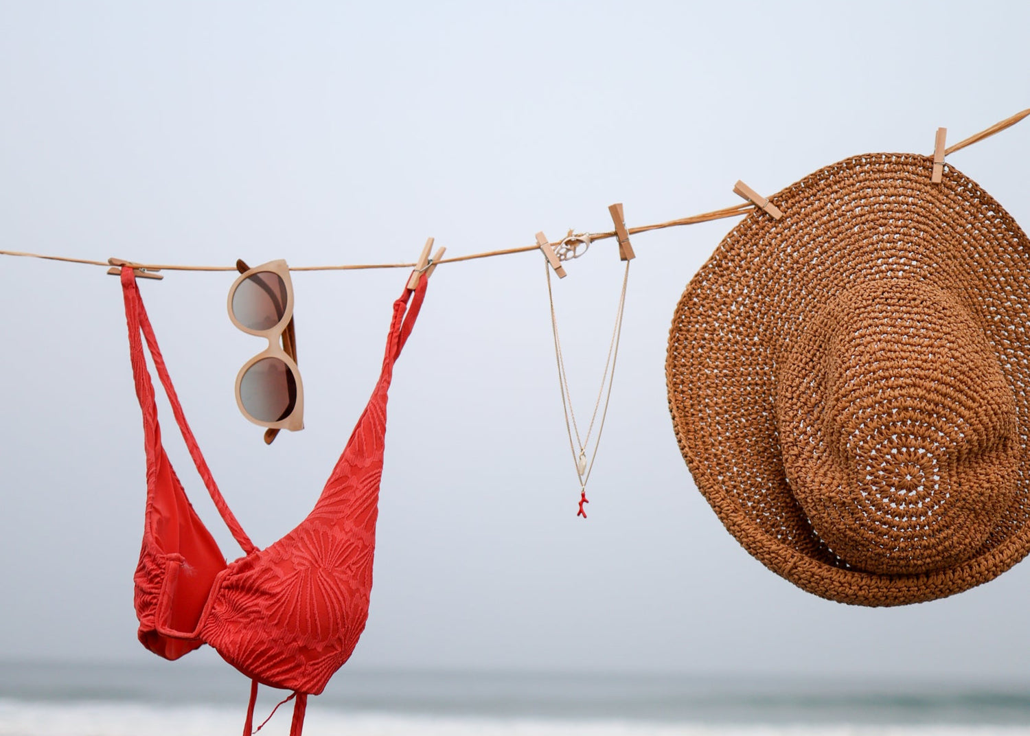 Red bikini and straw hat on a clothesline with ocean view